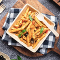 Pasta dish with vegetables in a biodegradable ChicLeaf Palm Leaf Bowl on a checkered cloth