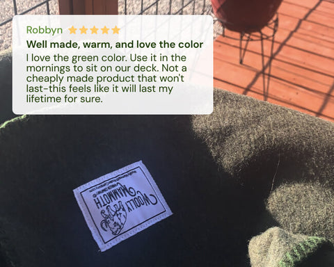Woolly Mammoth blanket on a green cushion outdoors, featuring a five-star rating text overlay.