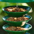 Three-tiered green bird feeder filled with mealworms.