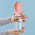 MalsiPree's pink coloured pet water bottle with attached bowl, held by a person against a blue background.