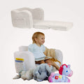 Child sitting on a plush todale lounge chair plus bed, with toys around, featuring a book and stuffed animals.