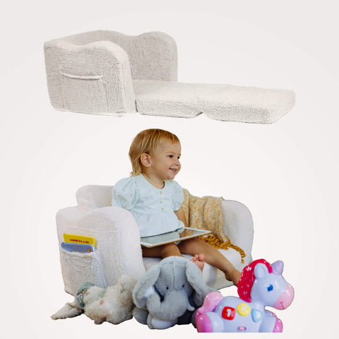Child sitting on a plush todale lounge chair plus bed, with toys around, featuring a book and stuffed animals.